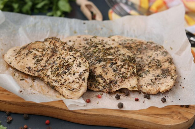 Filet de poulet aux herbes aromatiques sur parchemin sur une planche de bois