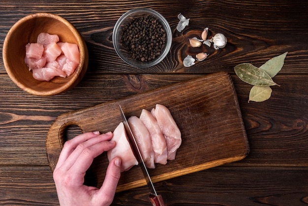 Filet de poulet cru sur une planche de bois sombre