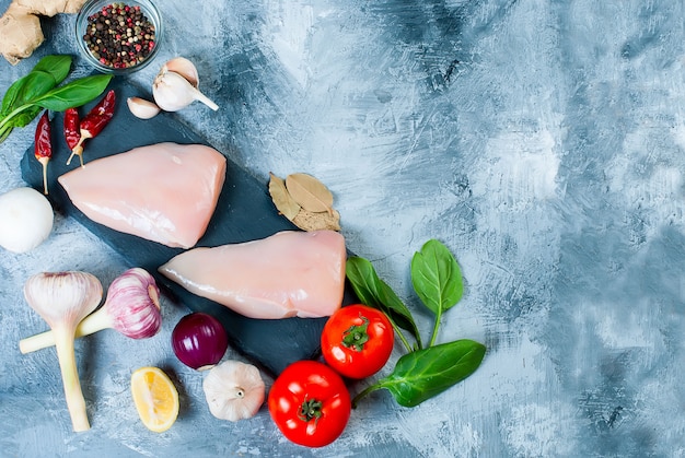 Filet de poulet cru sur une planche à découper avec des épices et des herbes.