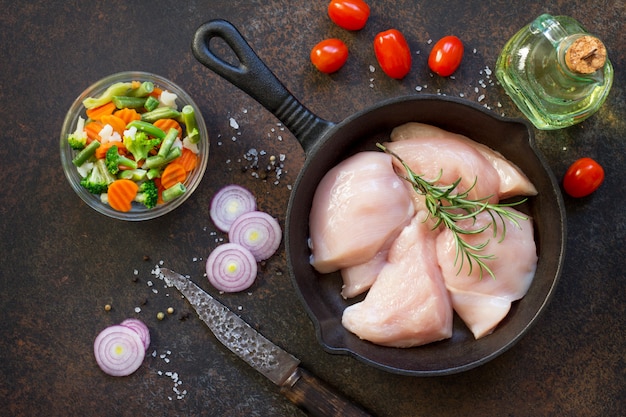 Filet de poulet cru sur une poêle en fonte