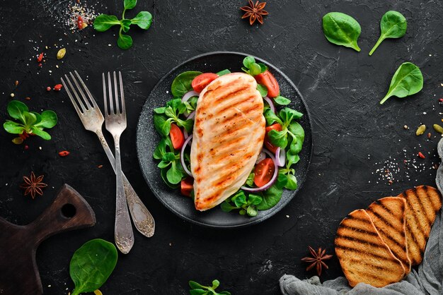 Filet de poulet cuit au four avec des légumes Dans une assiette noire sur un fond en bois Vue de dessus Espace libre pour votre texte Mise à plat