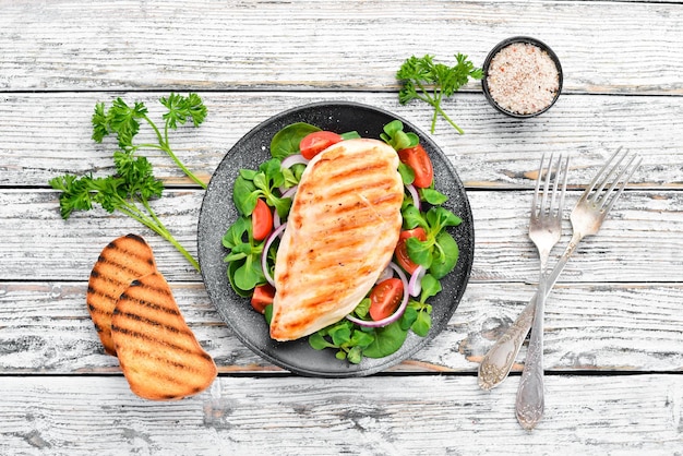 Filet de poulet cuit au four avec des légumes Dans une assiette noire sur un fond en bois Vue de dessus Espace libre pour votre texte Mise à plat