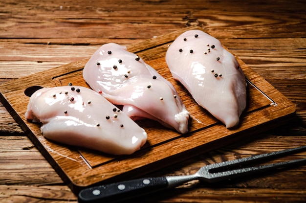 Filet de poulet frais avec des épices sur une table en bois