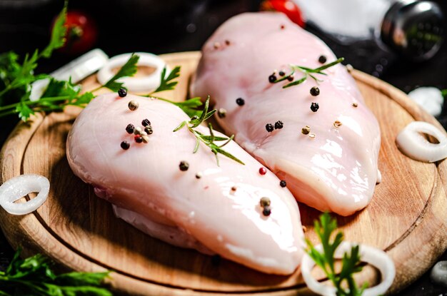 Un filet de poulet frais avec des épices sur une table noire