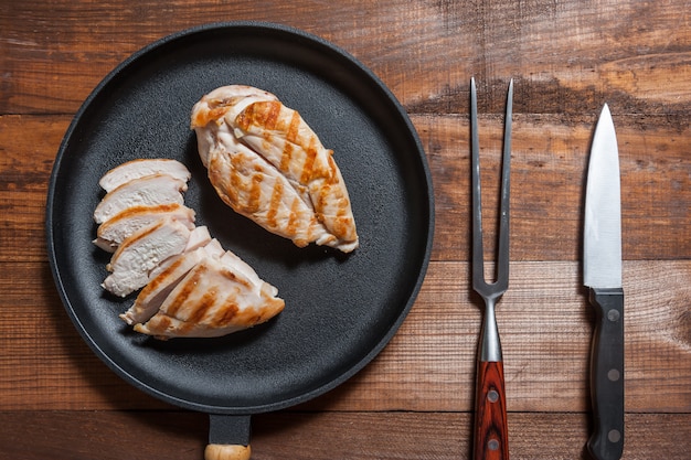 Filet de poulet grillé sur poêle, viande cuite. Fond en bois, pose à plat