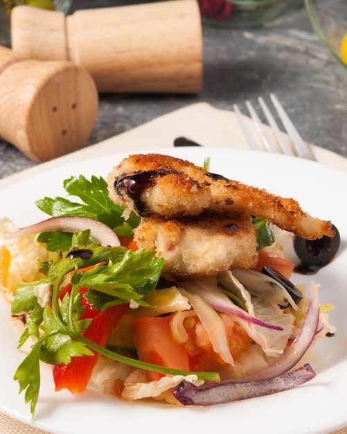 Filet de poulet pané savoureux avec des légumes frais sur une plaque blanche