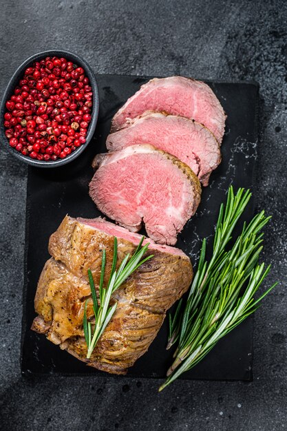 Filet de rosbif Viande de filet sur une planche de marbre. Fond noir. Vue de dessus.