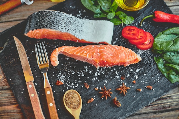 Filet de saumon cru et ingrédients pour la cuisson sur une table sombre