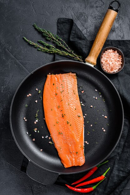 Filet de saumon cru avec sel et piment dans une poêle. Poisson biologique