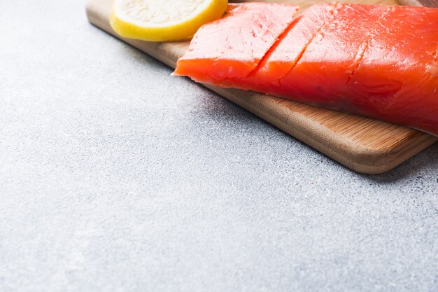 Filet de saumon frais au citron sur une planche à découper.