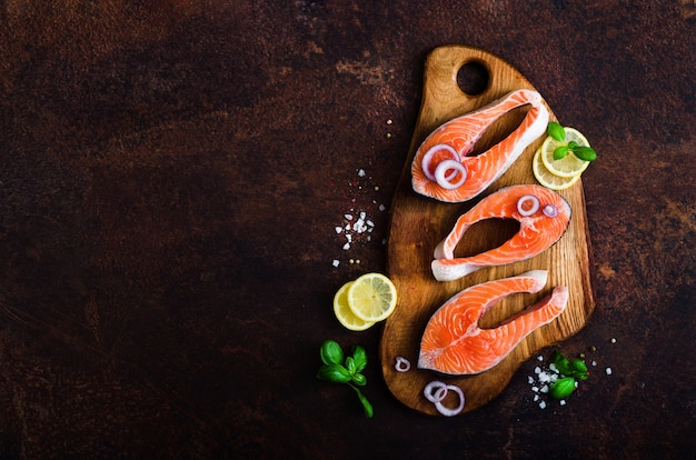 Filet de saumon frais cru avec des herbes aromatiques, des épices, du sel et du citron sur bois. Concept d&#39;aliments sains, régime ou cuisine, produit protéique. Fond