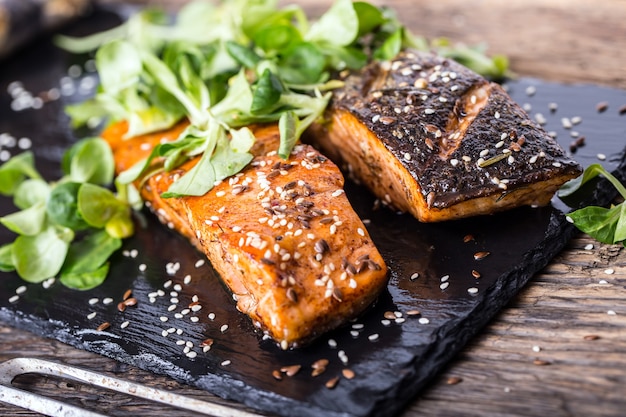 Filet de saumon grillé graines de sésame décoration d'herbes sur casserole vintage ou ardoise noire