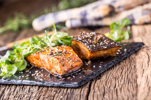 Filet de saumon grillé graines de sésame décoration d'herbes sur casserole vintage ou ardoise noire