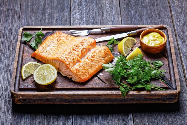 Filet de saumon grillé sur une planche à découper en bois grossier avec de la moutarde et du citron