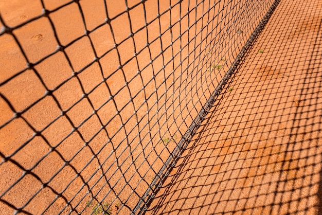 Filet de tennis sur terre battue rouge avec des lignes et des ombres