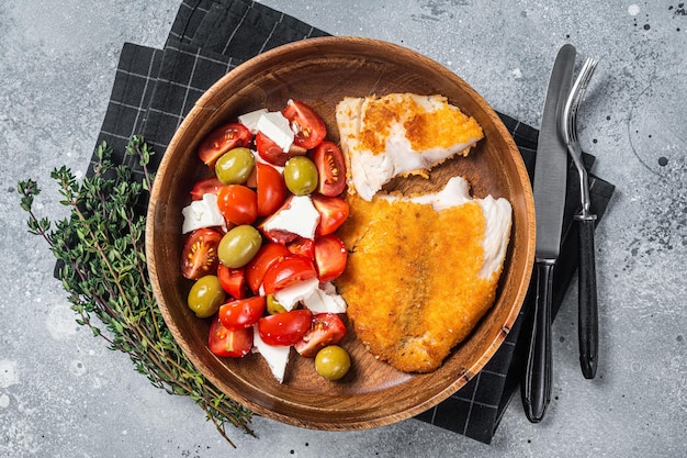 Filet de tilapia frit sur une assiette avec salade Fond gris Vue de dessus