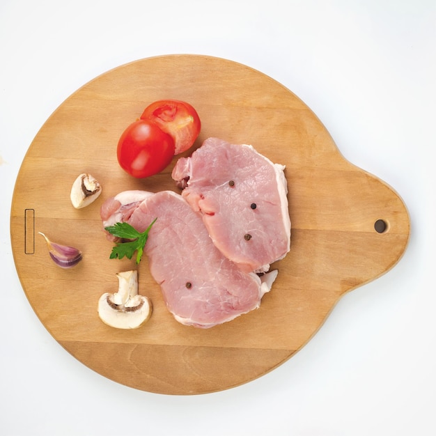 Filet de viande de veau crue pour griller avec des ustensiles sur une planche rustique légère