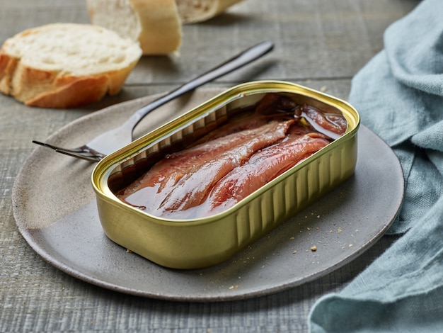 Photo filets d'anchois en conserve et tranches de baguette sur une table de cuisine en bois