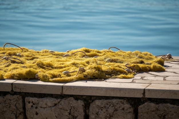 Les filets de pêche sèchent sur le rivage. Filet de pêche près du quai. Filets de pêche de couleur jaune empilés