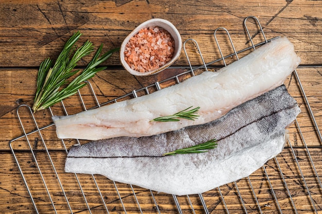 Filets de poisson cru sur le gril avec du romarin et des herbes Fond en bois Vue de dessus