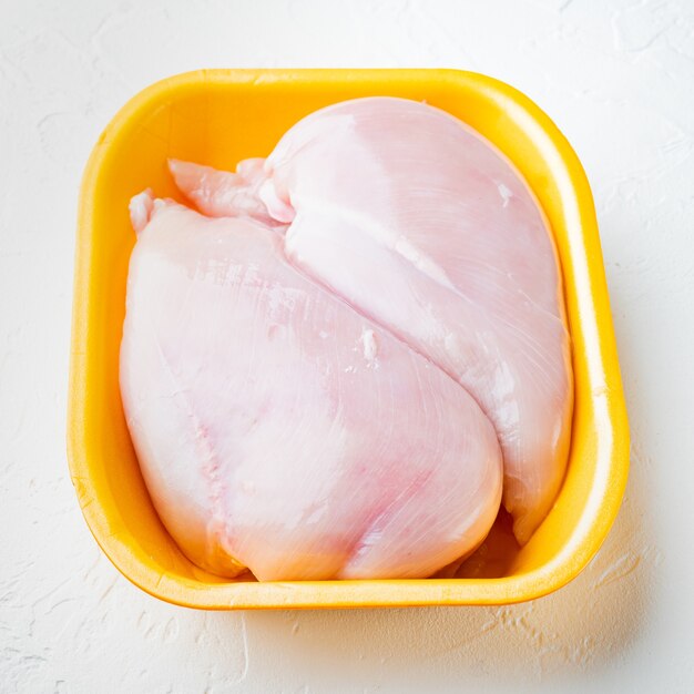 Filets de poitrine de poulet cru dans le bac, sur fond blanc