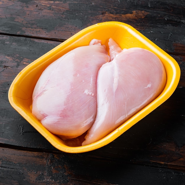 Filets de poitrine de poulet cru dans le bac, sur fond de bois foncé