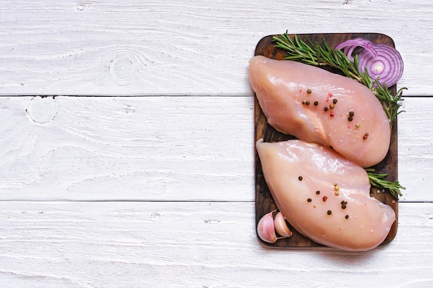 Filets de poulet cru sur une planche à découper en bois