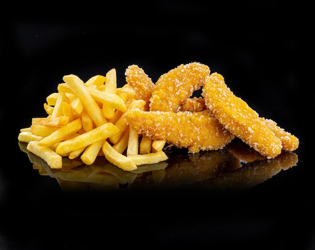 Filets de poulet nuggets panés et frites sur fond noir