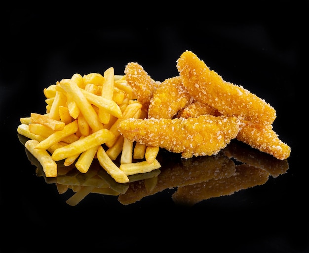 Filets de poulet nuggets panés et frites sur fond noir