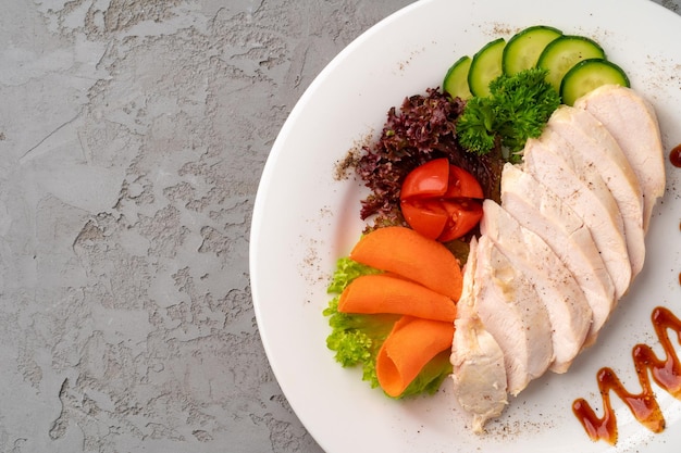 Filets de poulet rôti et légumes sur fond gris