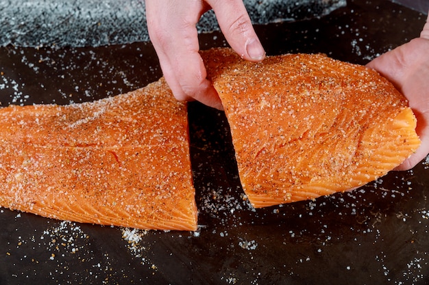 Les filets de saumon coupés à la main sur un tableau noir.