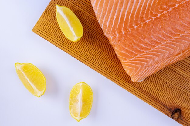 Filets de saumon cru en planche à découper en bois sur blanc