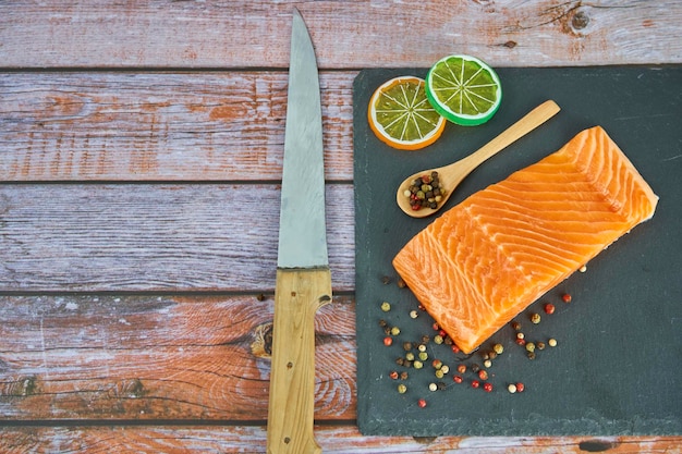 Filets de saumon frais sur planche à découper noire avec herbes et épices