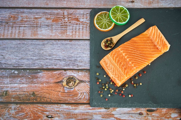 Filets de saumon frais sur planche à découper noire avec herbes et épices