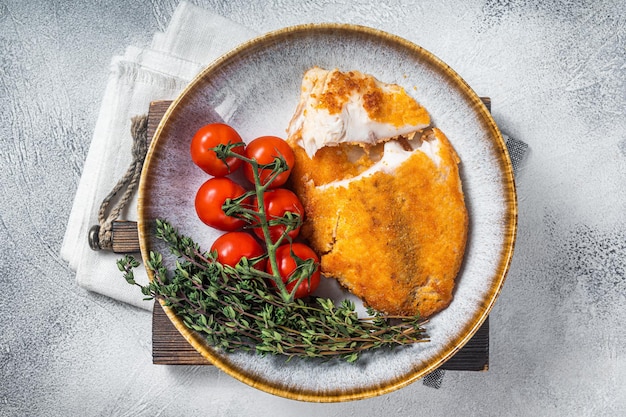 Filets de tilapia panés croustillants sur une assiette avec des légumes Fond blanc Vue de dessus