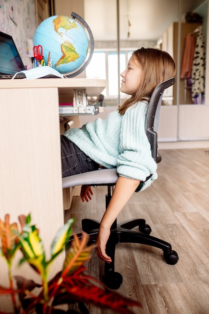 Fille de 10 ans dans un masque sur l'apprentissage à distance à la maison. L'enfant s'ennuie, il est fatigué