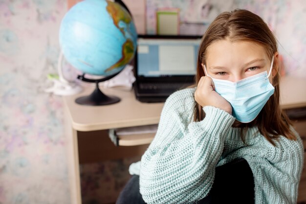 Fille de 10 ans dans un masque sur l'apprentissage à distance à la maison. L'enfant s'ennuie, il est fatigué