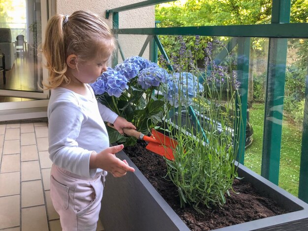 Fille de 3 ans plante des fleurs sur le balcon