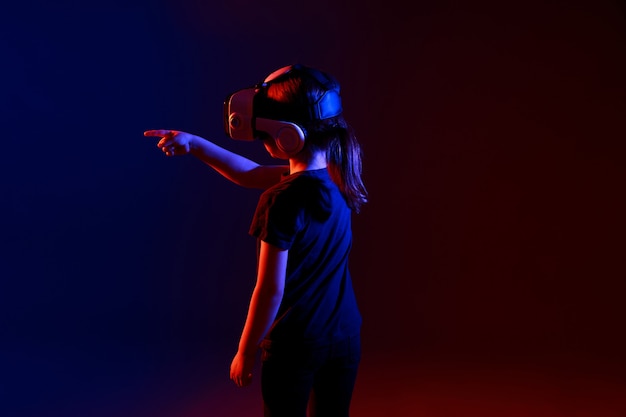 Fille de 5 ans expérimentant le jeu de casque VR sur une surface colorée. Enfant utilisant un gadget de jeu pour la réalité virtuelle. Lunettes futuristes à un jeune âge. Technologie virtuelle.