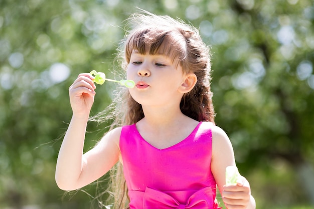 Une fille de 5 ans laisse échapper des bulles de savon.