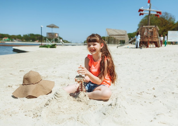 Une fille de 7 ans joue dans le sable sur une plage de la ville Vacances et repos Enfant actif ludique sur la plage en vacances d'été