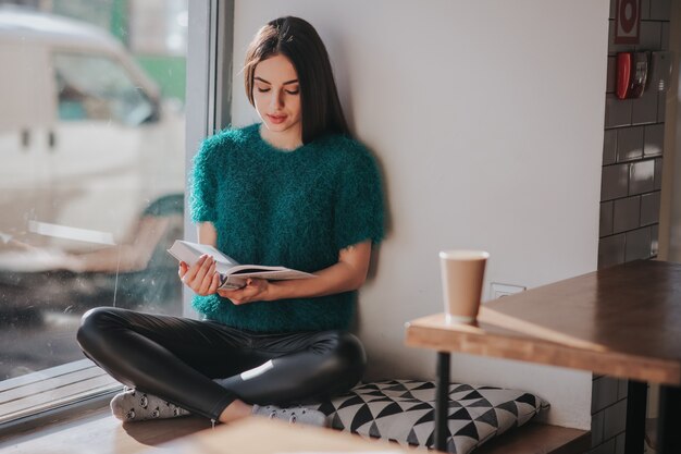 Fille absorbée dans le livre de lecture pendant la pause au café