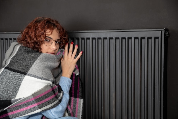 Une fille accroupie autour d'un radiateur chaud Le premier démarrage du système de chauffage central