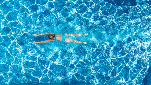 Fille active dans la piscine drone aérien vue d'en haut, jeune femme nage dans l'eau bleue