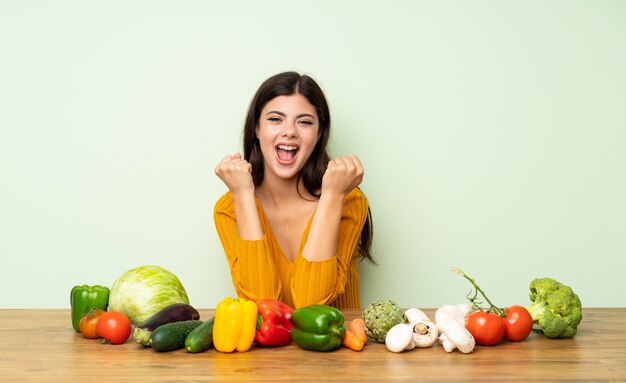 Fille adolescente avec beaucoup de légumes célébrant une victoire en position de vainqueur