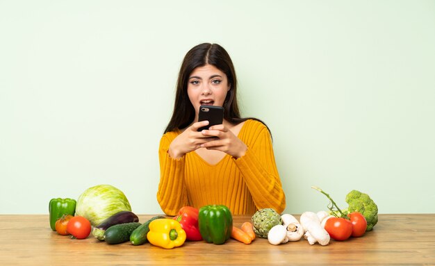 Fille adolescente avec beaucoup de légumes surpris et envoyant un message