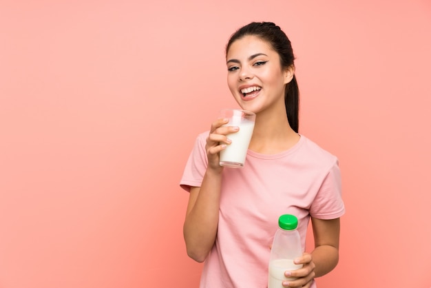 Fille adolescente heureuse sur mur rose isolé, prenant le lait de petit déjeuner