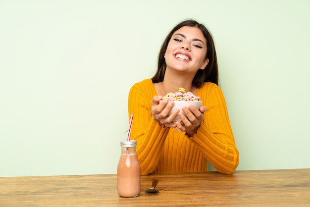 Fille adolescente heureuse prenant son petit déjeuner avec bol de céréales