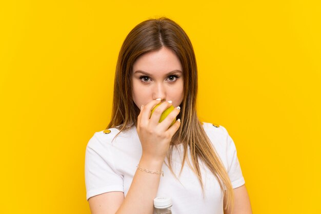 Fille adolescente sur un mur jaune avec une pomme