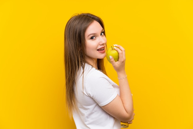 Fille adolescente sur un mur jaune avec une pomme